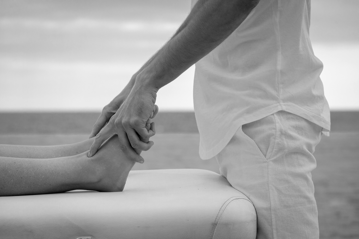 Osteópata de Osteoquantum tratando el pie de un paciente junto al mar